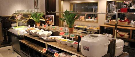 A buffet setup with various food items and a coffee machine.