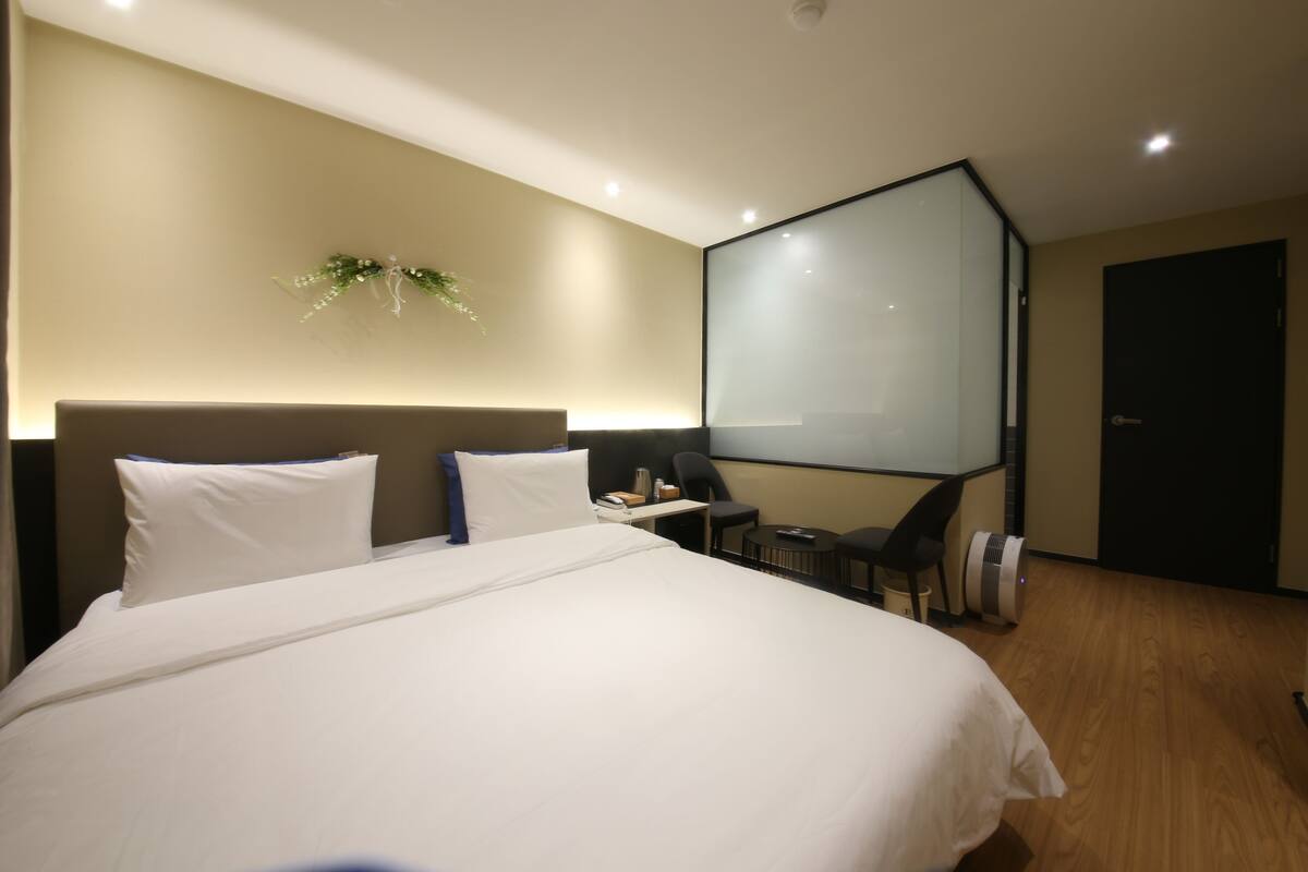 A modern hotel room with a large bed, a desk, and a flat-screen TV.