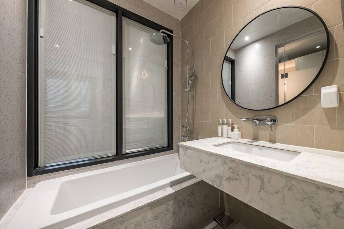 A modern bathroom with a large bathtub, a glass-enclosed shower, and a marble vanity.