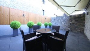 A patio area with a round table and six chairs, surrounded by potted spherical plants. - Brown Dot Hotel Masan (Changwon)