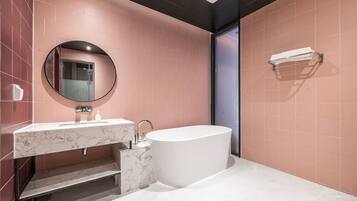 A modern bathroom with a marble vanity, a freestanding bathtub, and a round mirror.