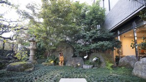 A garden with a stone lantern, large rocks, and a pathway leading to a building. - Hotel Hakata Nakasu Inn (Fukuoka)