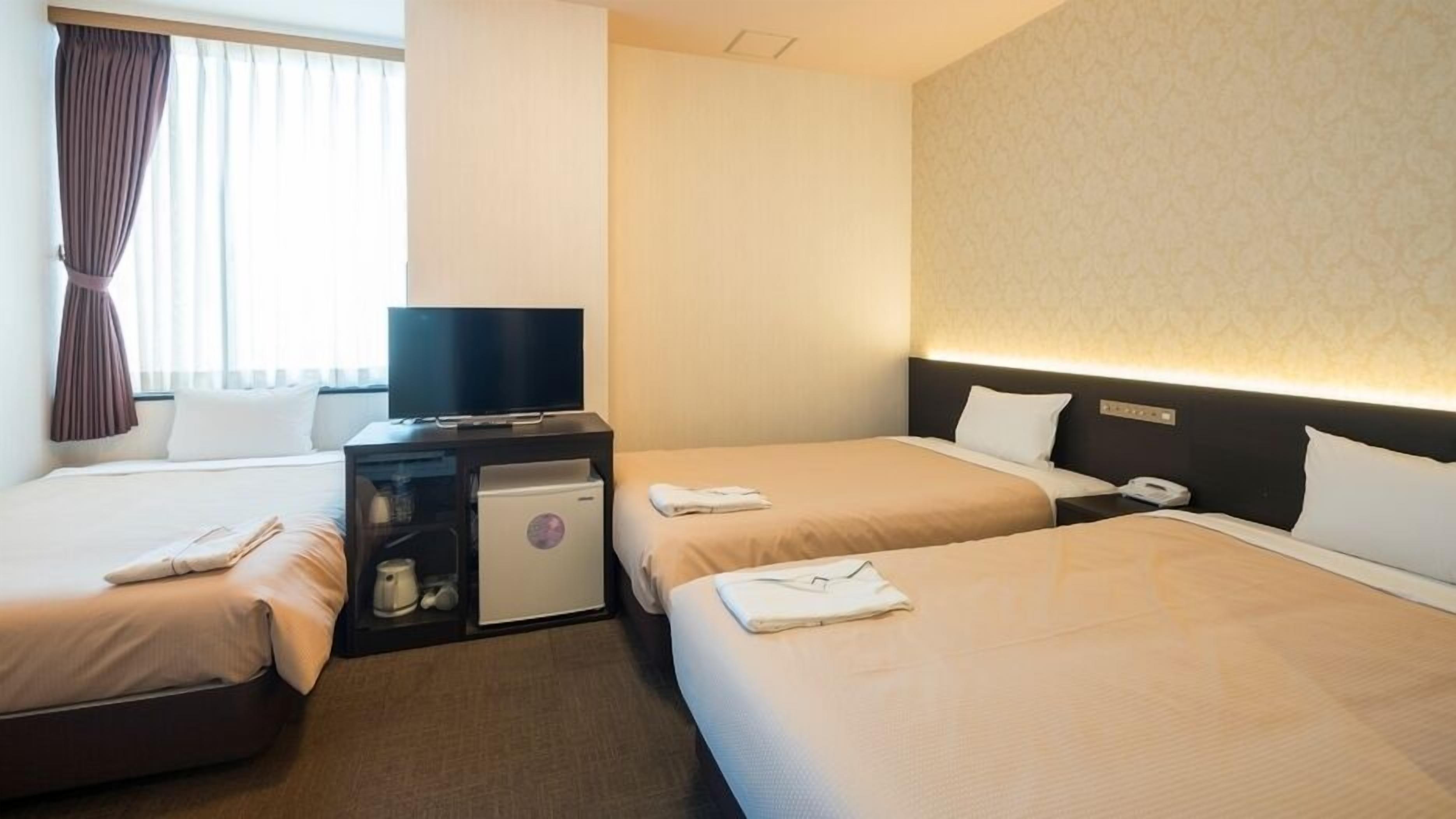 Habitació d'hotel amb dos llits, televisió, minibar i escriptori.