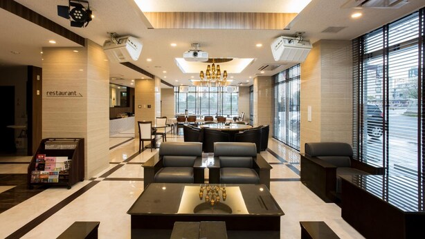 A modern hotel lobby with a reception desk, seating area, and a view of the city through large windows. - Hotel Hakata Nakasu Inn (Fukuoka)