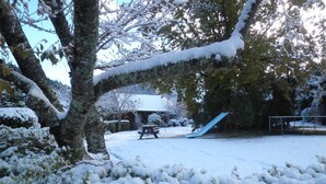 A snow-covered outdoor area with a picnic table, a slide, and a swing set. - Forest Peak Motel (Hanmer Springs)