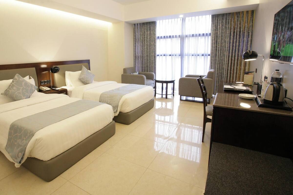Una habitación de hotel con dos camas, un escritorio, una silla y un televisor.