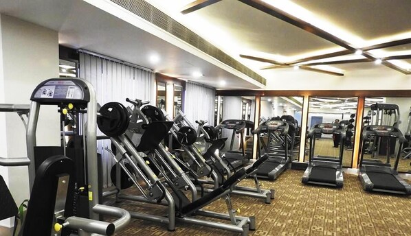 Un gimnasio con diverso equipo de ejercicio, incluyendo cintas de correr, máquinas de pesas y pesas libres.