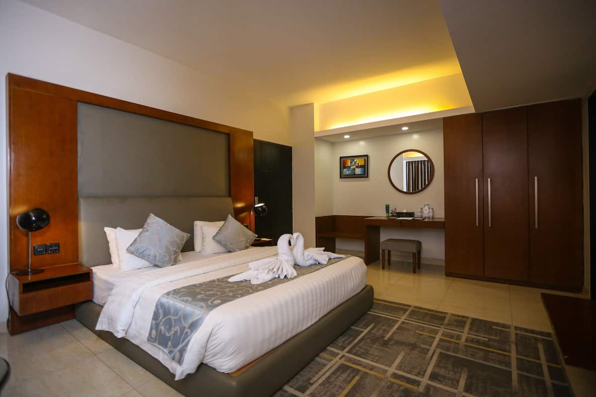 Una habitación de hotel moderna con una cama grande, un escritorio, un espejo y un armario.