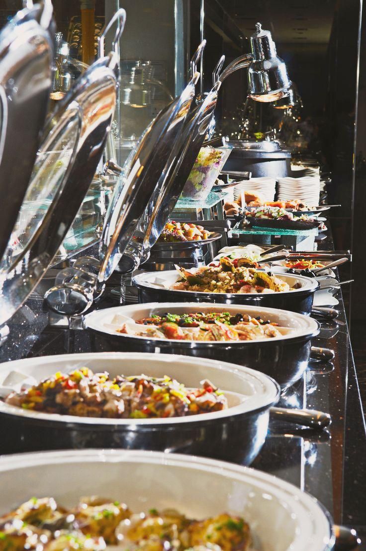 A buffet line with various dishes and utensils.