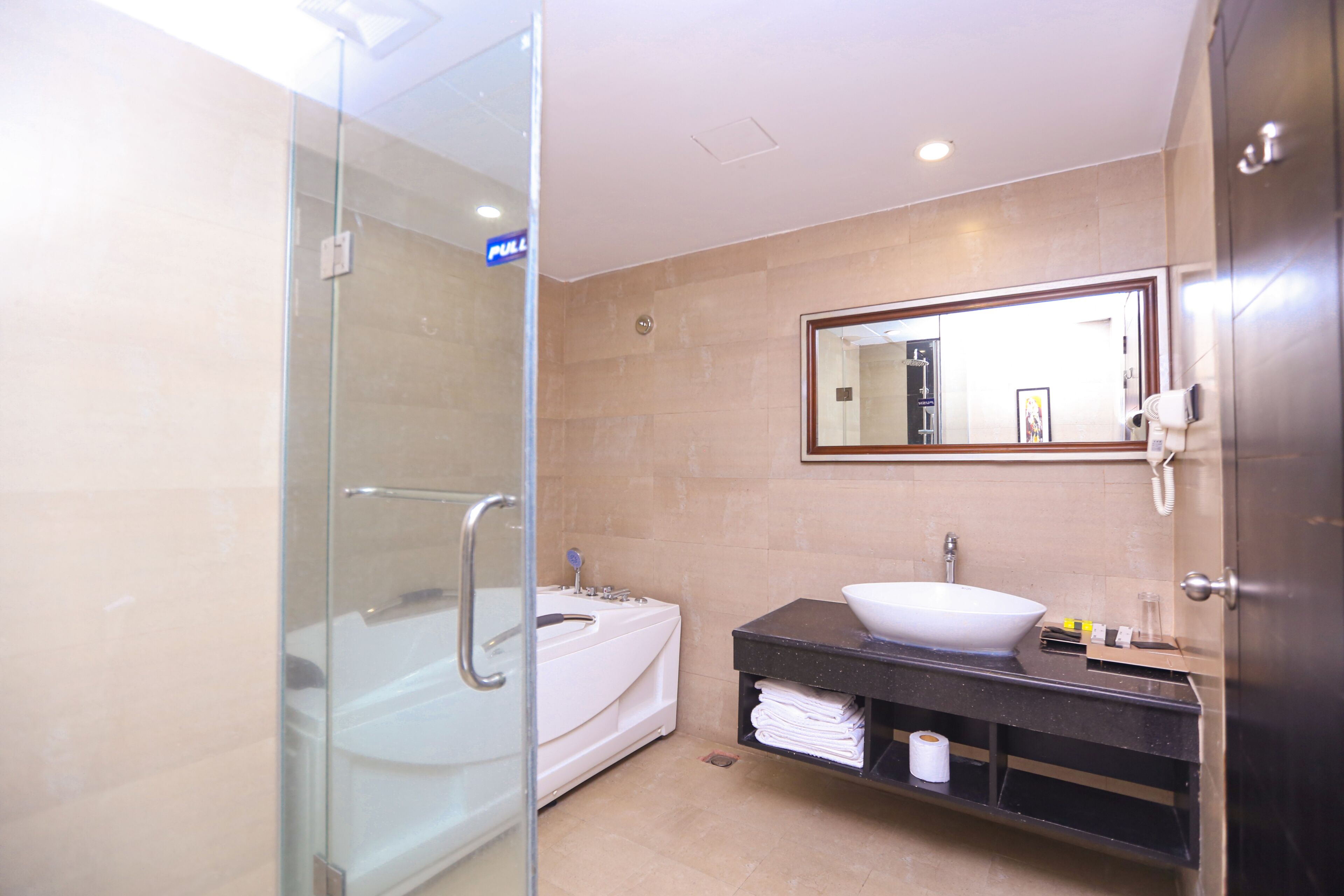 A modern bathroom with a glass-enclosed shower, a white bathtub, and a black vanity with a white sink.
