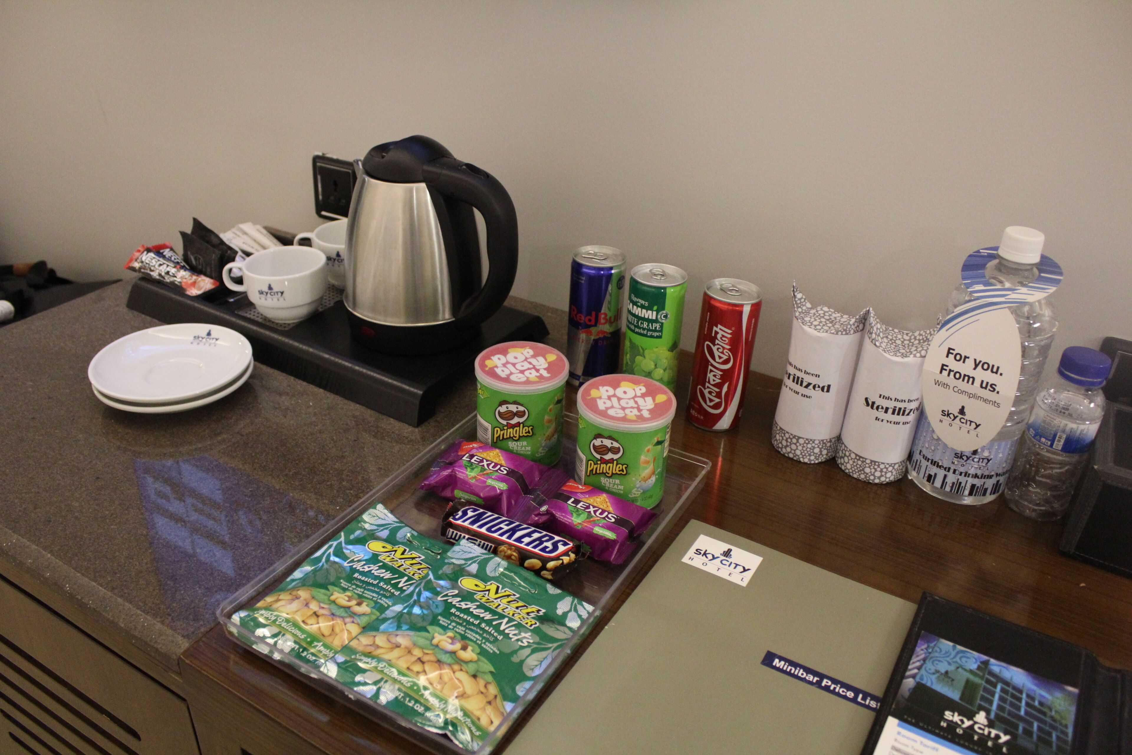 A hotel reception area with a coffee station, snacks, and bottled water.