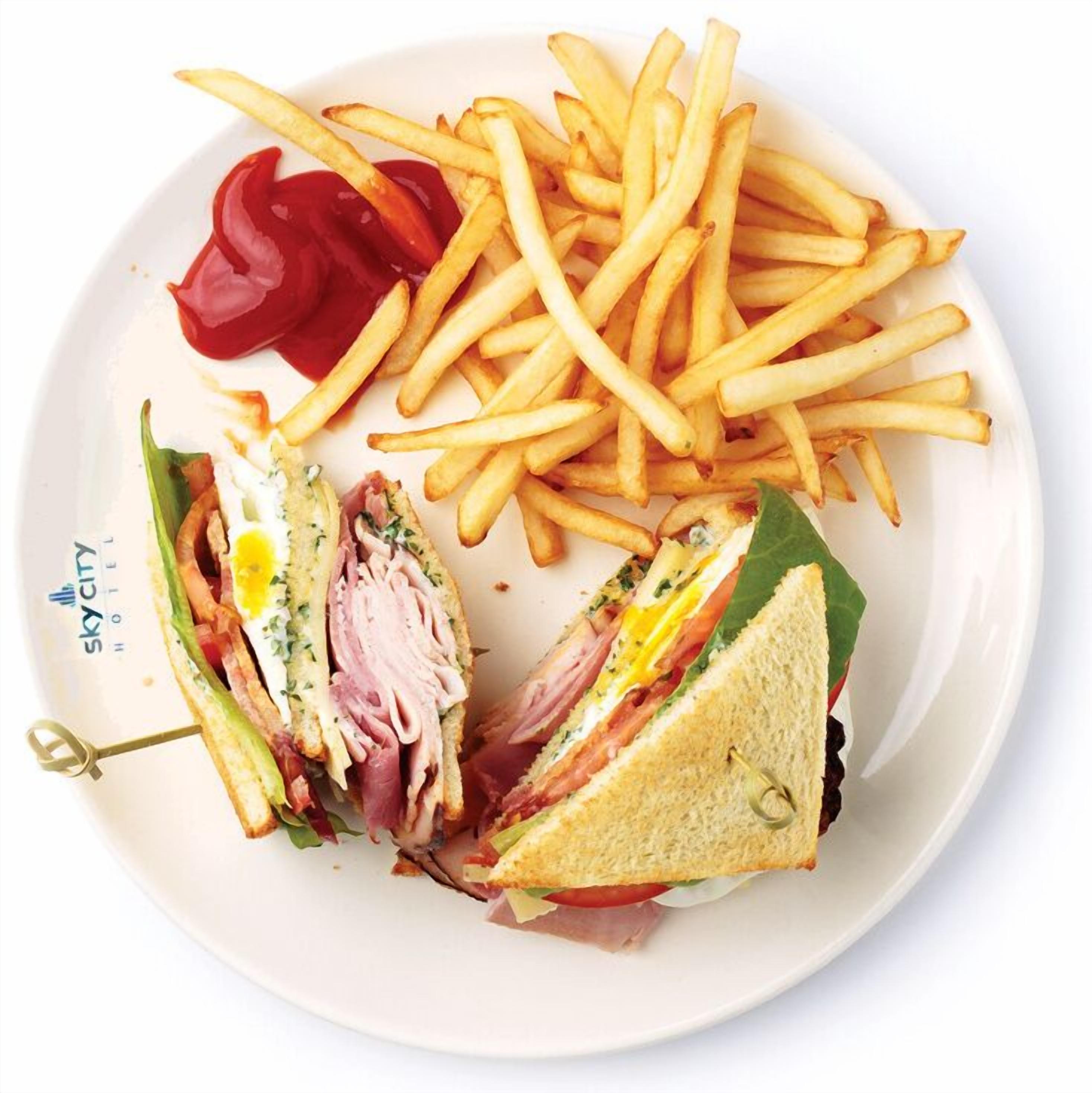 A plate with a sandwich cut in half, french fries, and a side of ketchup.