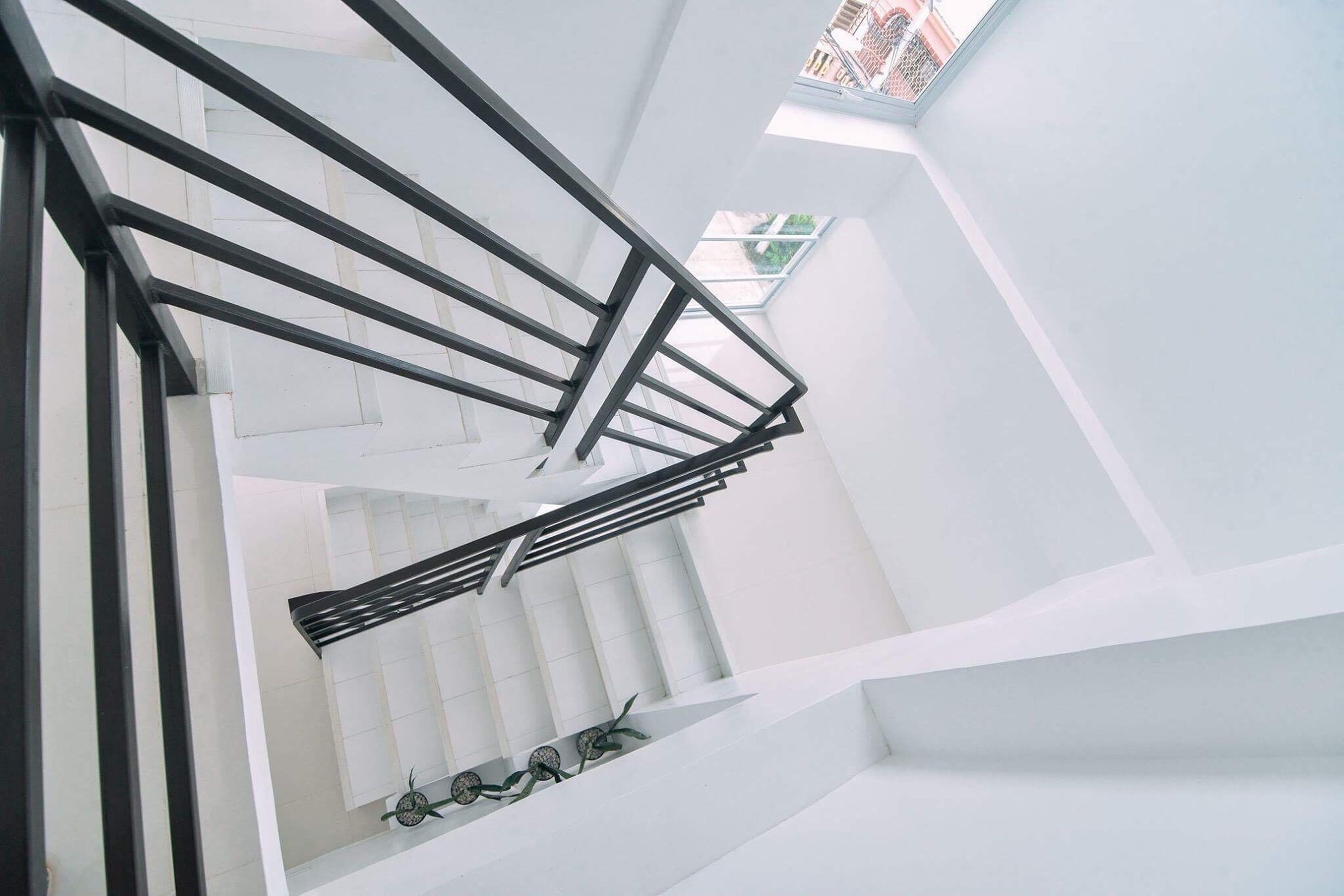 A modern staircase with a black metal railing and white walls.