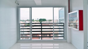 A room with a large window, white walls, and a red cabinet. - The Strand Suites and Dormitel (Davao)