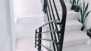 A staircase with black railings and white steps, leading to a landing with potted plants. - The Strand Suites and Dormitel (Davao)