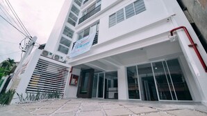 A modern building with a sign indicating a business is open. - The Strand Suites and Dormitel (Davao)