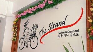 A wall with a logo for 'The Strand Suites & Dormitel' featuring a bicycle and floral decorations. - The Strand Suites and Dormitel (Davao)