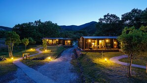 A secluded cabin with a porch and a dining area, surrounded by a gravel path and trees.