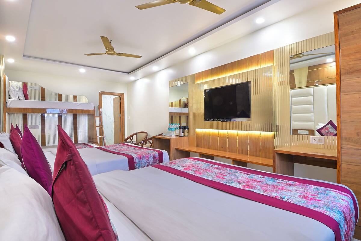 A hotel room with two beds, a TV, a wooden headboard, and a ceiling fan.