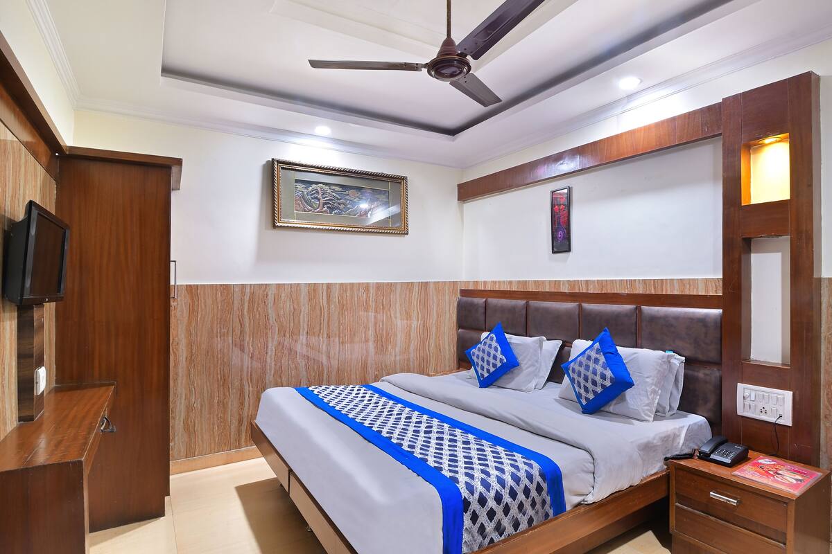 A hotel room with a bed, bedside table, nightstand, and a ceiling fan.