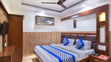 A hotel room with a bed, bedside table, nightstand, and a ceiling fan.