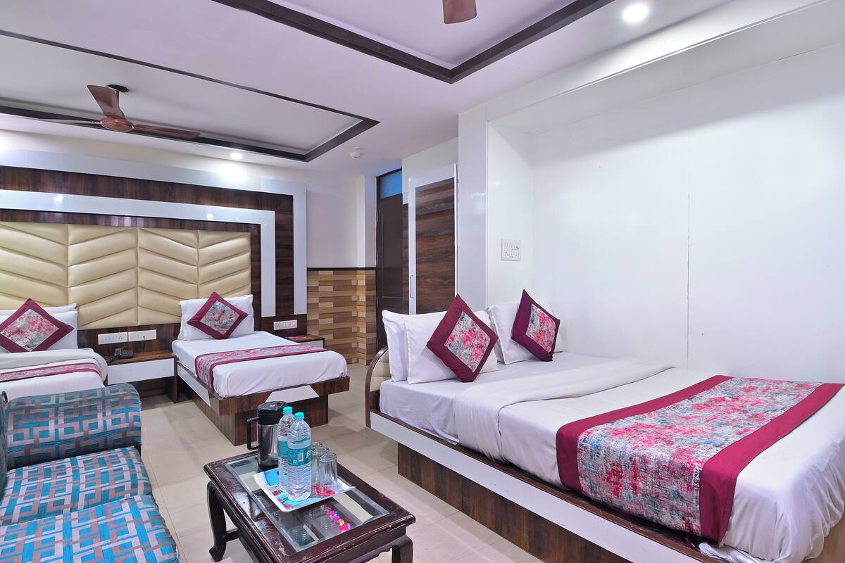 A hotel room with two beds, a sofa, a coffee table, and a ceiling fan.