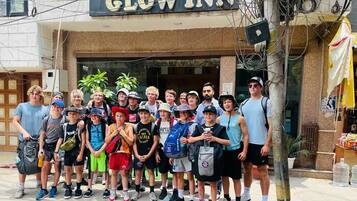 A group of people standing in front of a hotel named "Hotel Glow Inn".