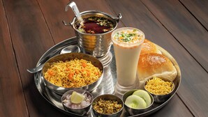 A meal tray with various Indian dishes including noodles, a milkshake, and a bread roll. - Hotel Glow Inn (New Delhi)