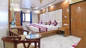 A hotel room with a large bed, two bedside tables, a wooden chair, a glass table, and a ceiling fan. - Hotel Glow Inn (New Delhi)