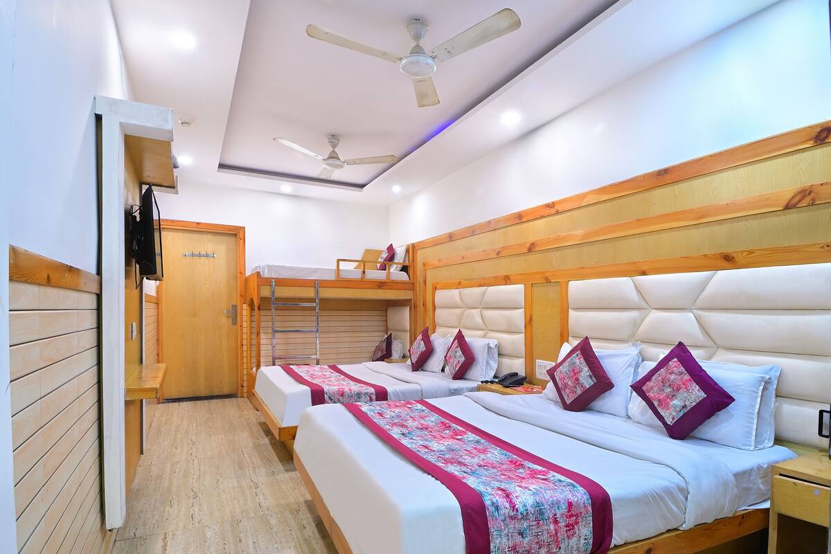 A hotel room with two beds, a wooden headboard, a ceiling fan, and a wooden wardrobe.