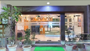 The entrance of Hotel Glow Inn with a sign above the door, potted plants in front, and a reception desk inside. - Hotel Glow Inn (New Delhi)