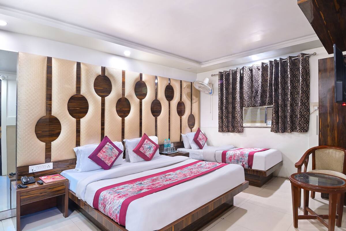 A hotel room with two beds, a wooden headboard, a small table, and a chair.