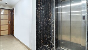 An elevator with a metallic finish and a wall with a black and gold marbled pattern. - Hotel Glow Inn (New Delhi)