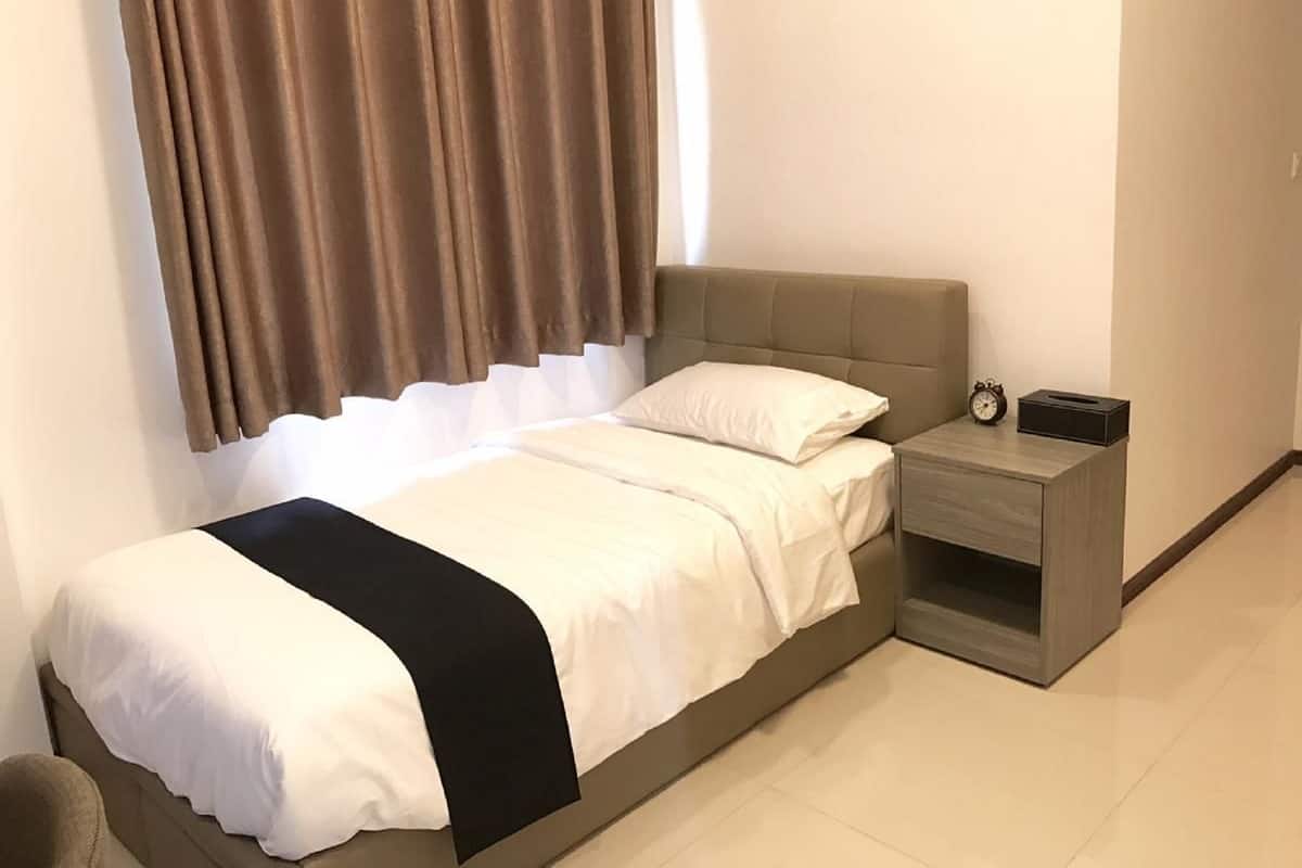 A neatly arranged bedroom with a bed, a bedside table with a clock, and a nightstand.