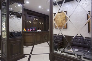 Een receptie met een incheckbalie, een zithoek met een bank en fauteuils, en een wandklok.