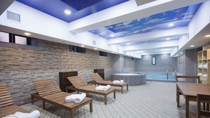 A spa area with wooden loungers, a hot tub, and a stone wall.