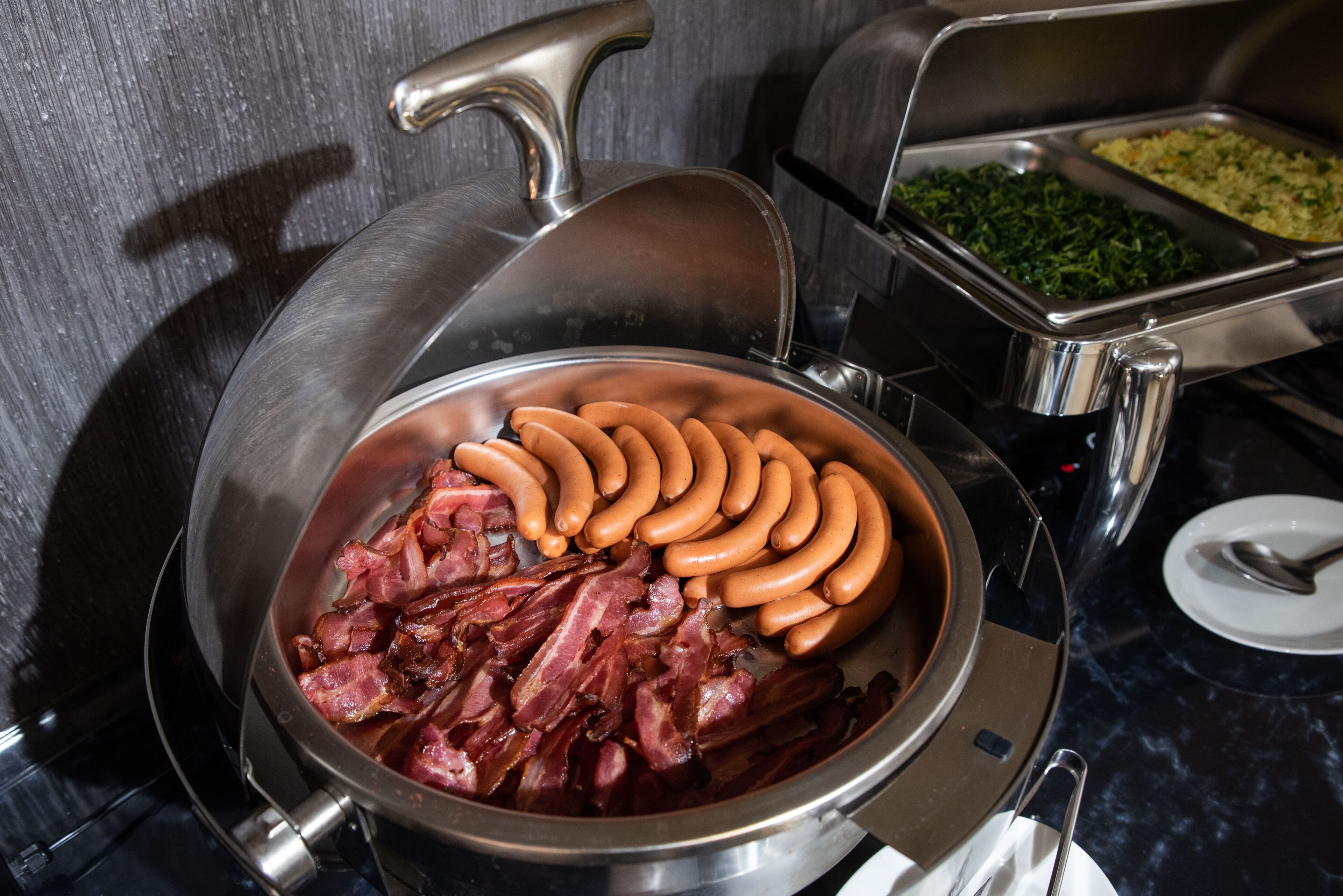 A buffet with various food items including sausages and bacon.