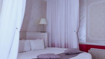 Un dormitorio con cama redonda, cortinas blancas y una pared de acento roja.