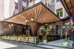 Un espace extérieur aménagé avec une terrasse couverte, des plantes en pot et un panneau indiquant « Hôtel Solruss ».