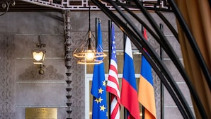 A seating area with a table, chairs, and colorful cushions. Flags of the United States, Russia, and Ukraine are displayed.