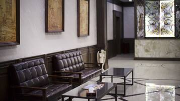 A lobby with leather seating, framed artwork, and a reception area with patterned glass.