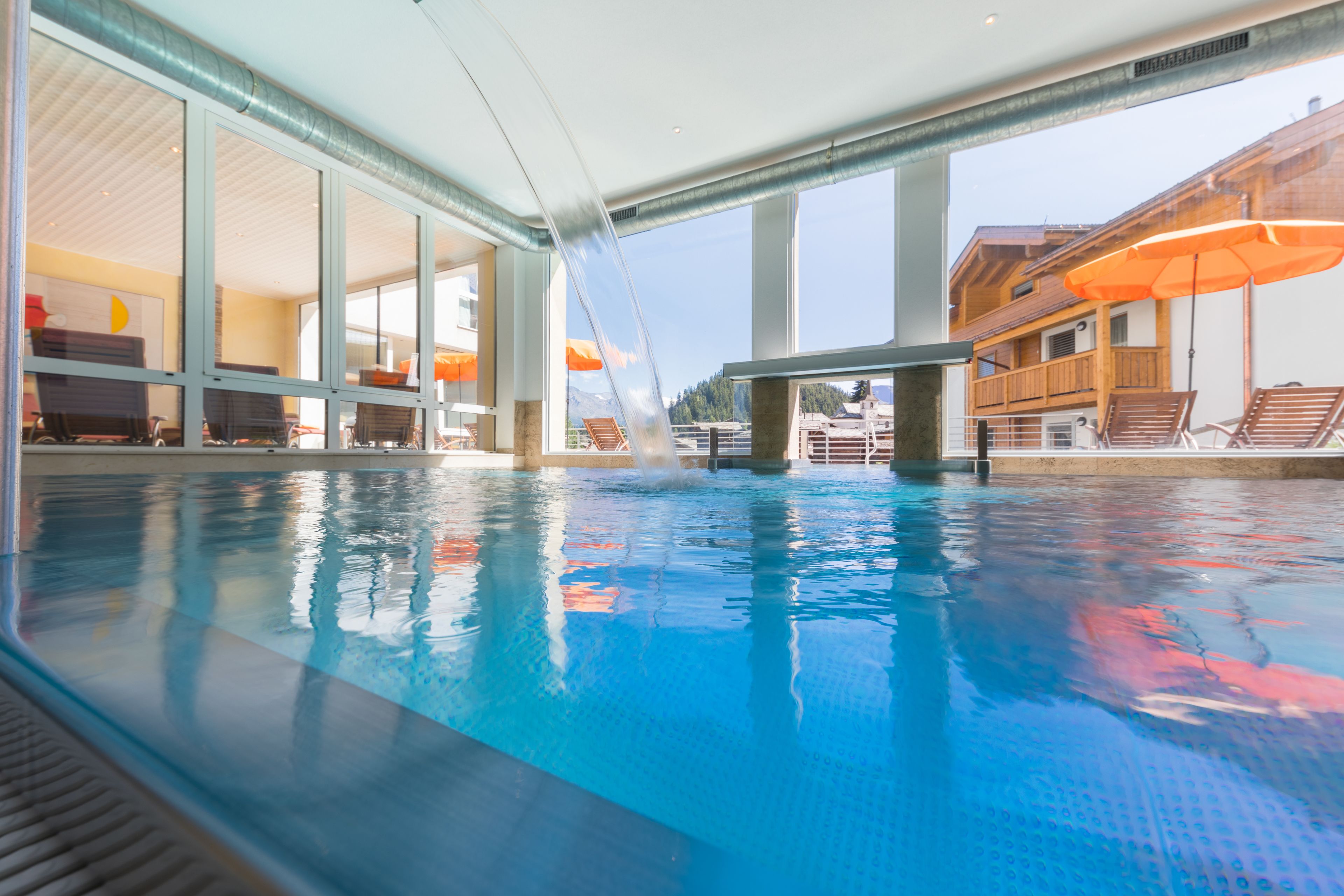 A swimming pool with clear water, a water slide, and outdoor seating with umbrellas.