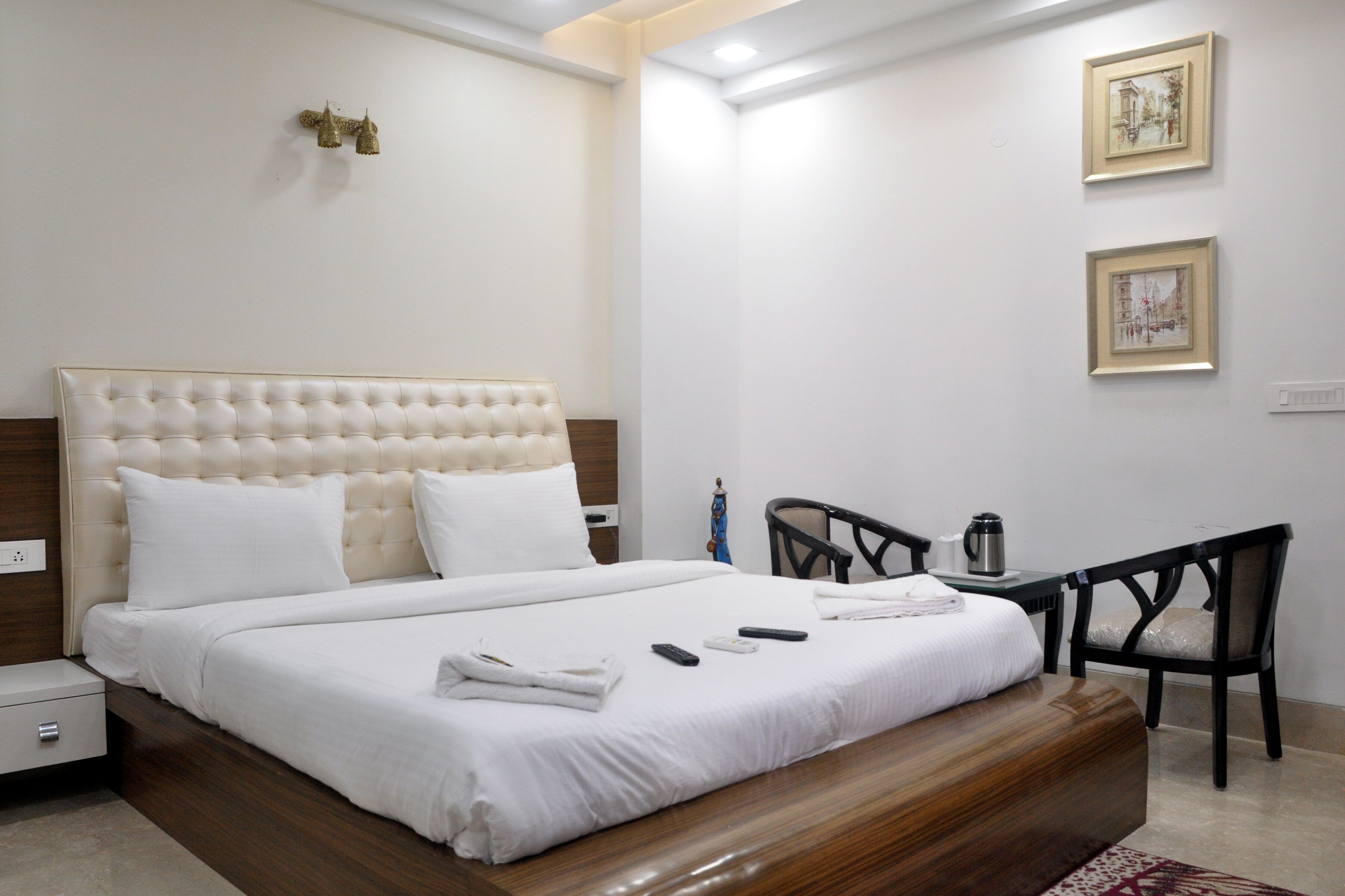 A neatly made bed with white linens, a wooden headboard, and a bedside table with a lamp.