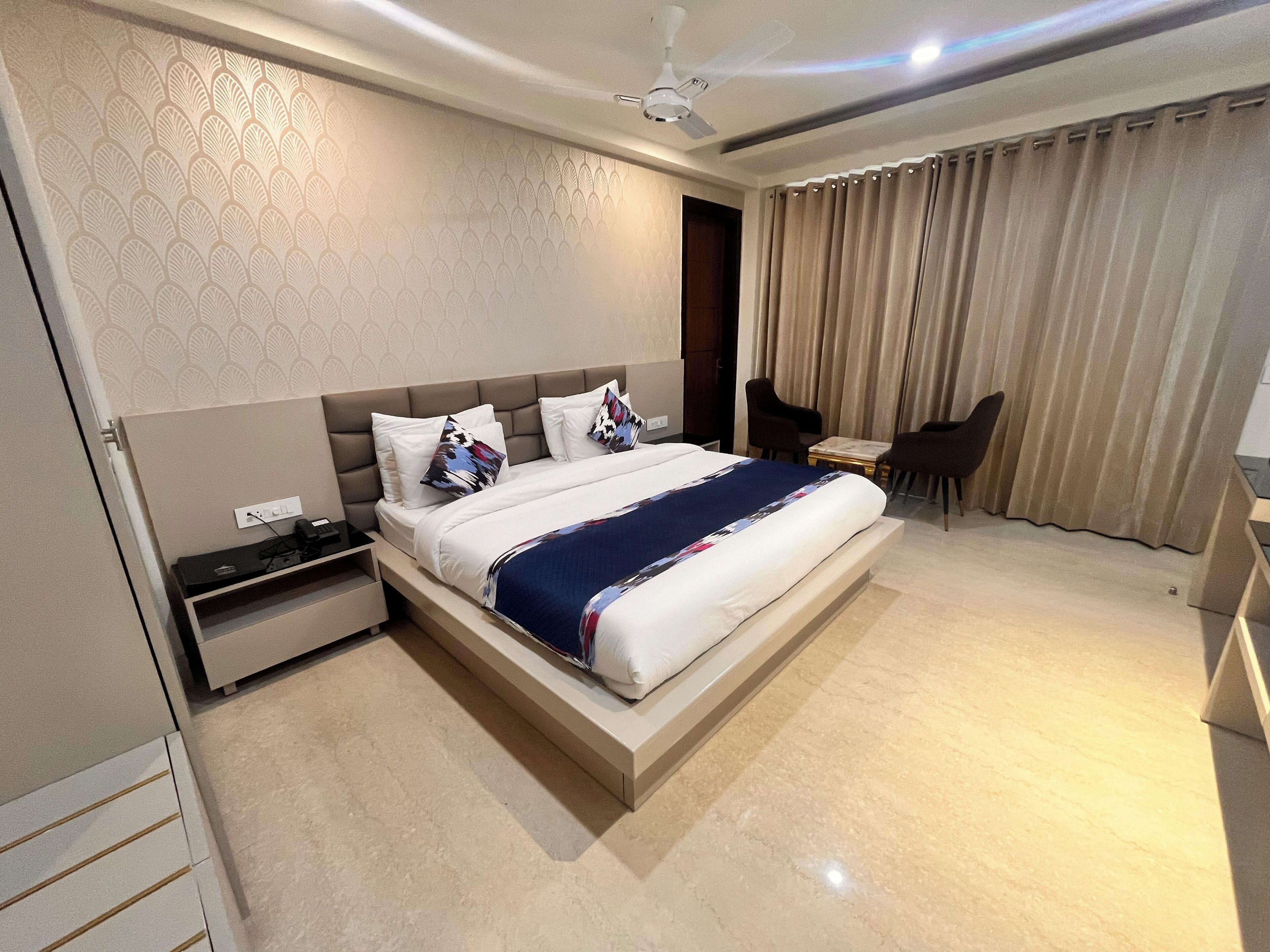 A modern hotel room with a large bed, bedside tables, a desk, and a chair.