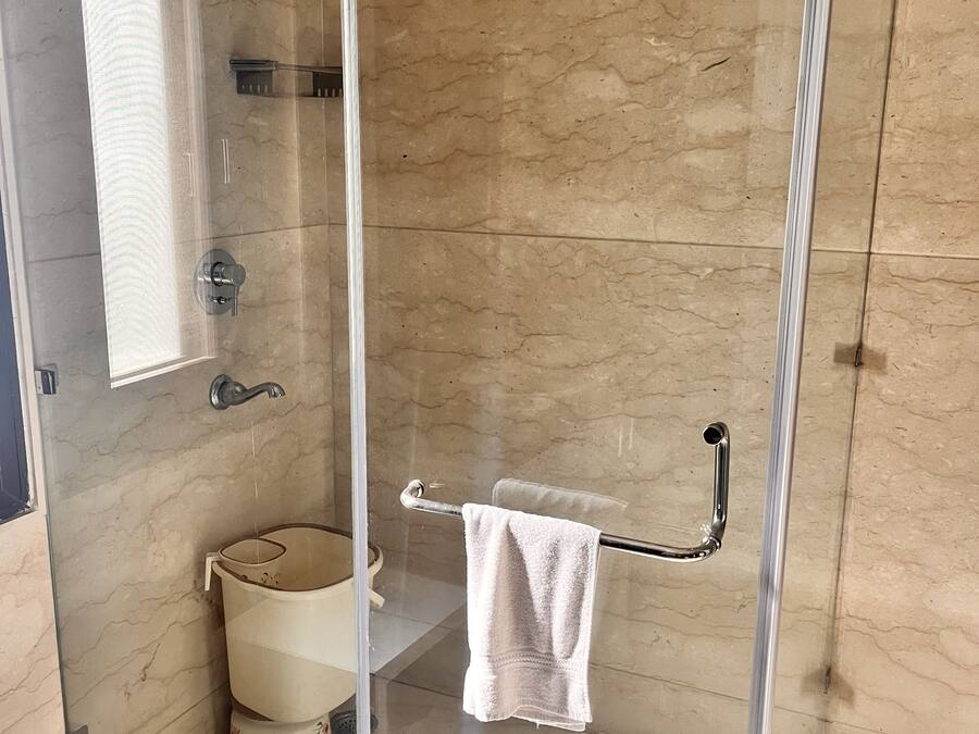 A glass-enclosed shower with a glass door, a towel rack, and a toilet with a floral design.