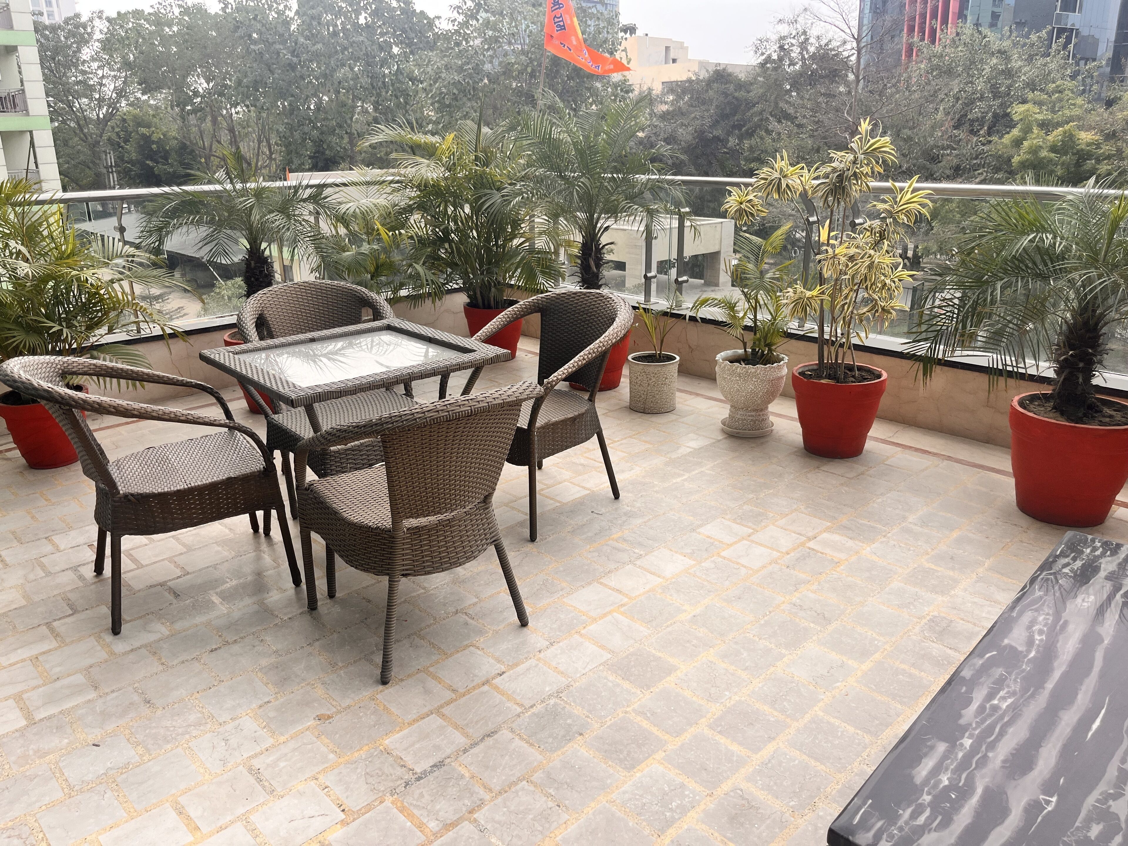 Eine Dachterrasse mit Korbmöbeln, Blumentöpfen und Blick auf die Stadtlandschaft.