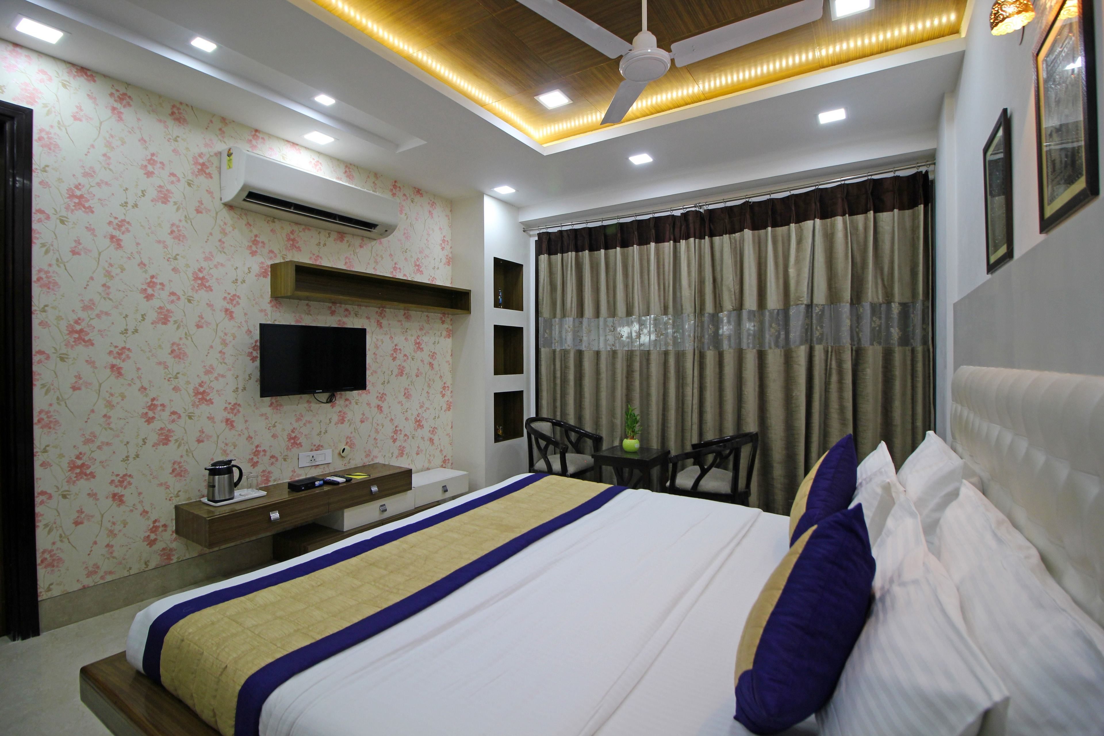 A hotel room with a bed, a desk, a chair, a television, and a window with curtains.