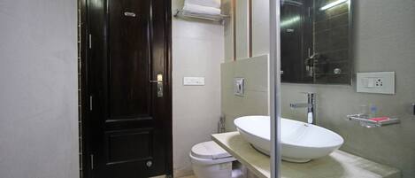 A bathroom with a dark wooden door, a white toilet, a large mirror, and a white sink with a countertop.