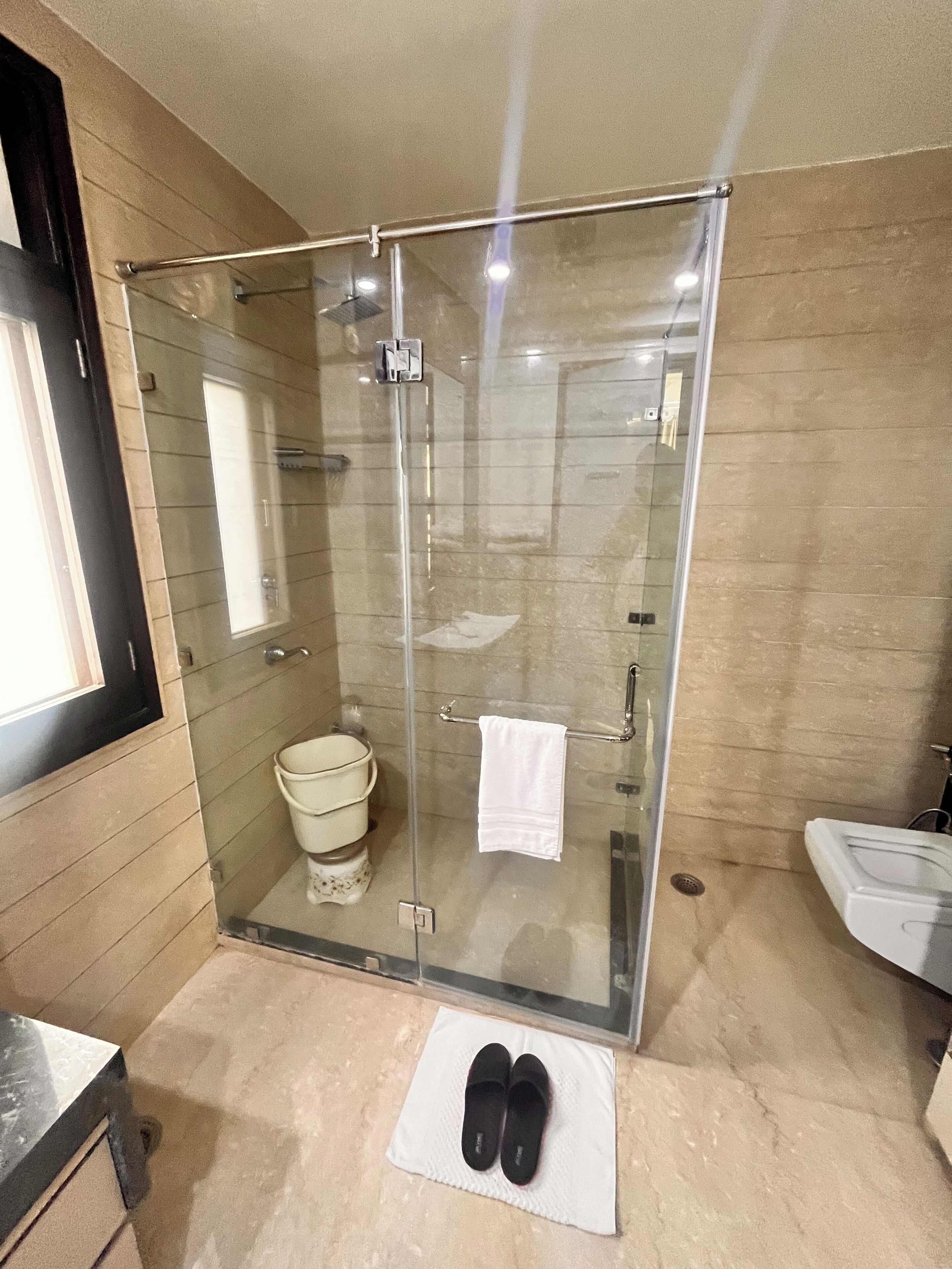 A modern bathroom with a glass-enclosed shower, a toilet, and a sink.