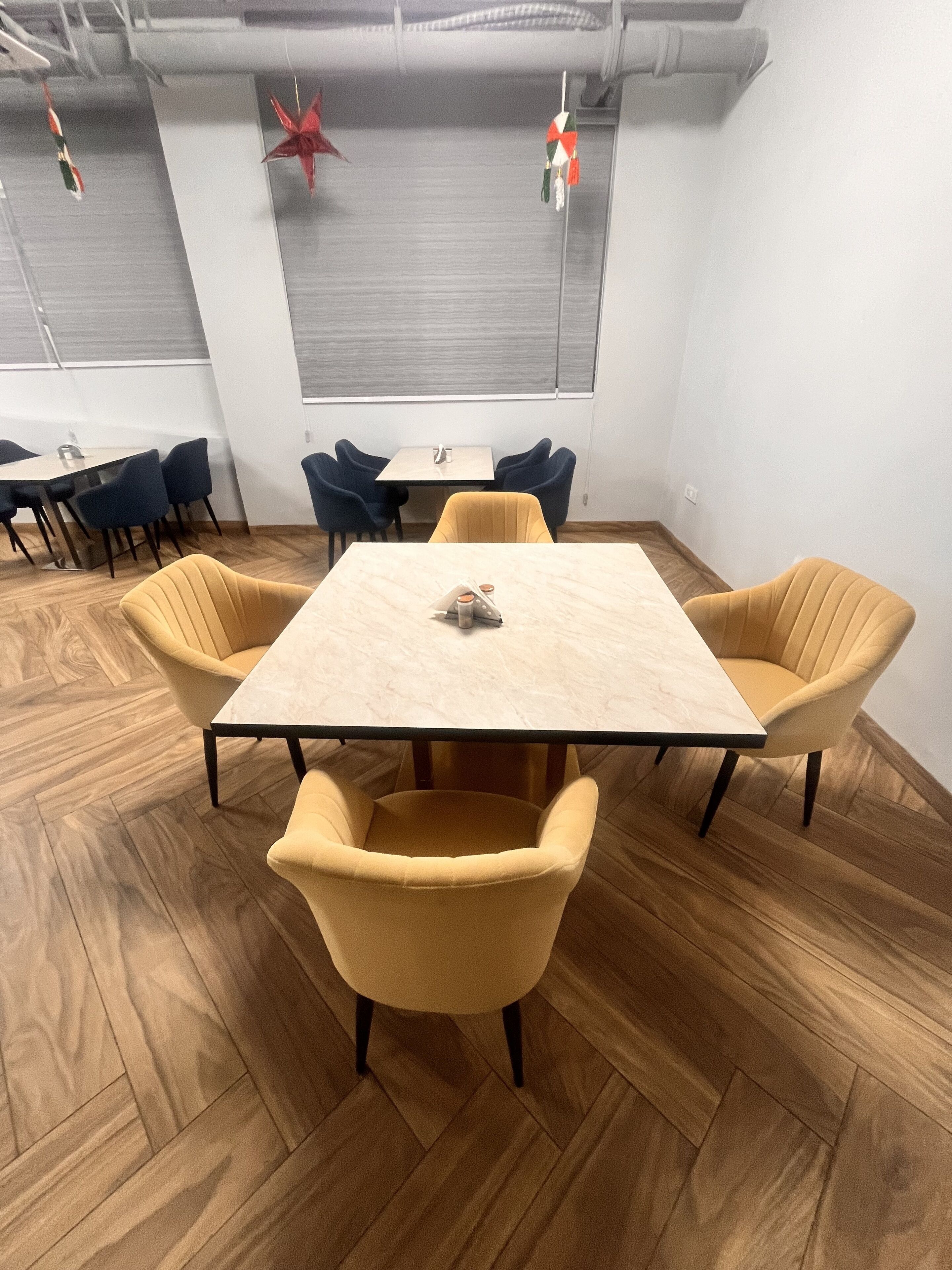 Une salle de conférence dotée d’un parquet en bois disposé en motif à chevrons, d’une table centrale et de quatre chaises jaunes.